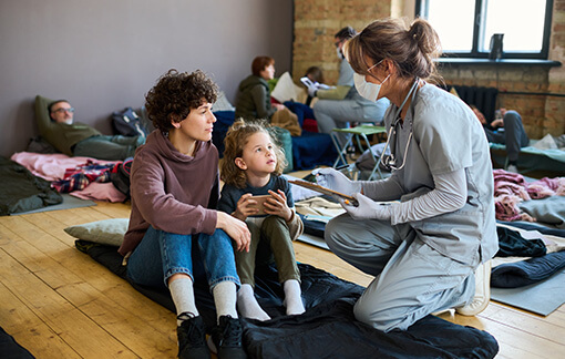 Volunteer Doctor at a shelter assisting a mother and child